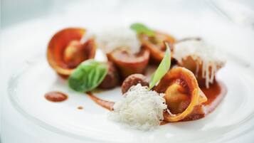 A plate of ravioli with sauce and grated cheese.