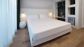 A modern hotel room with a large bed, a round ottoman, a wardrobe with a mirror, and a built-in heater.