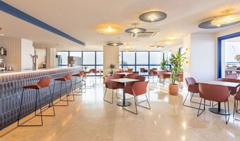 Un restaurant moderne doté d’un bar, de plusieurs espaces pour s’asseoir et de grandes fenêtres offrant une vue panoramique.
