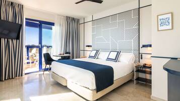 Habitación de hotel moderna con cama, escritorio, silla, televisor y vistas al exterior.