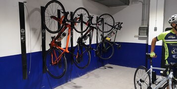 A bicycle storage area with multiple bikes and a person wearing a cycling jersey.