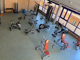 A gym with various exercise equipment, including treadmills, stationary bikes, and weight machines.