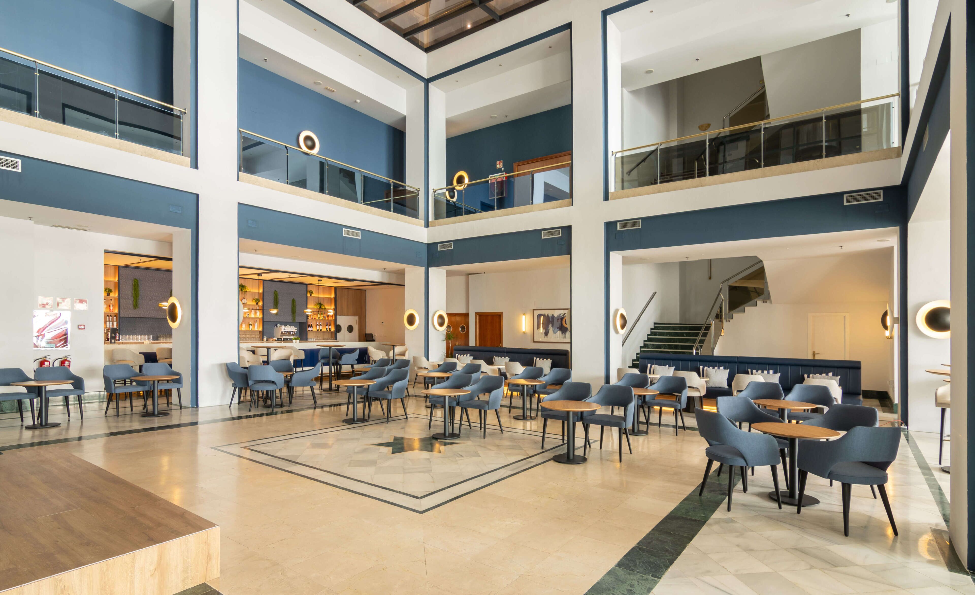 A spacious multi-level atrium with seating areas, a bar, and a staircase.