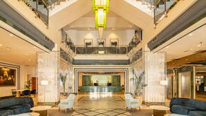 A spacious lobby with a high ceiling, a reception desk, multiple seating areas, and a staircase connecting floors. - Hotel Yaramar - Adults Recommended (Fuengirola)