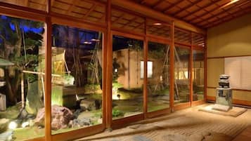 A room with large glass windows, wooden beams, and a small indoor garden.