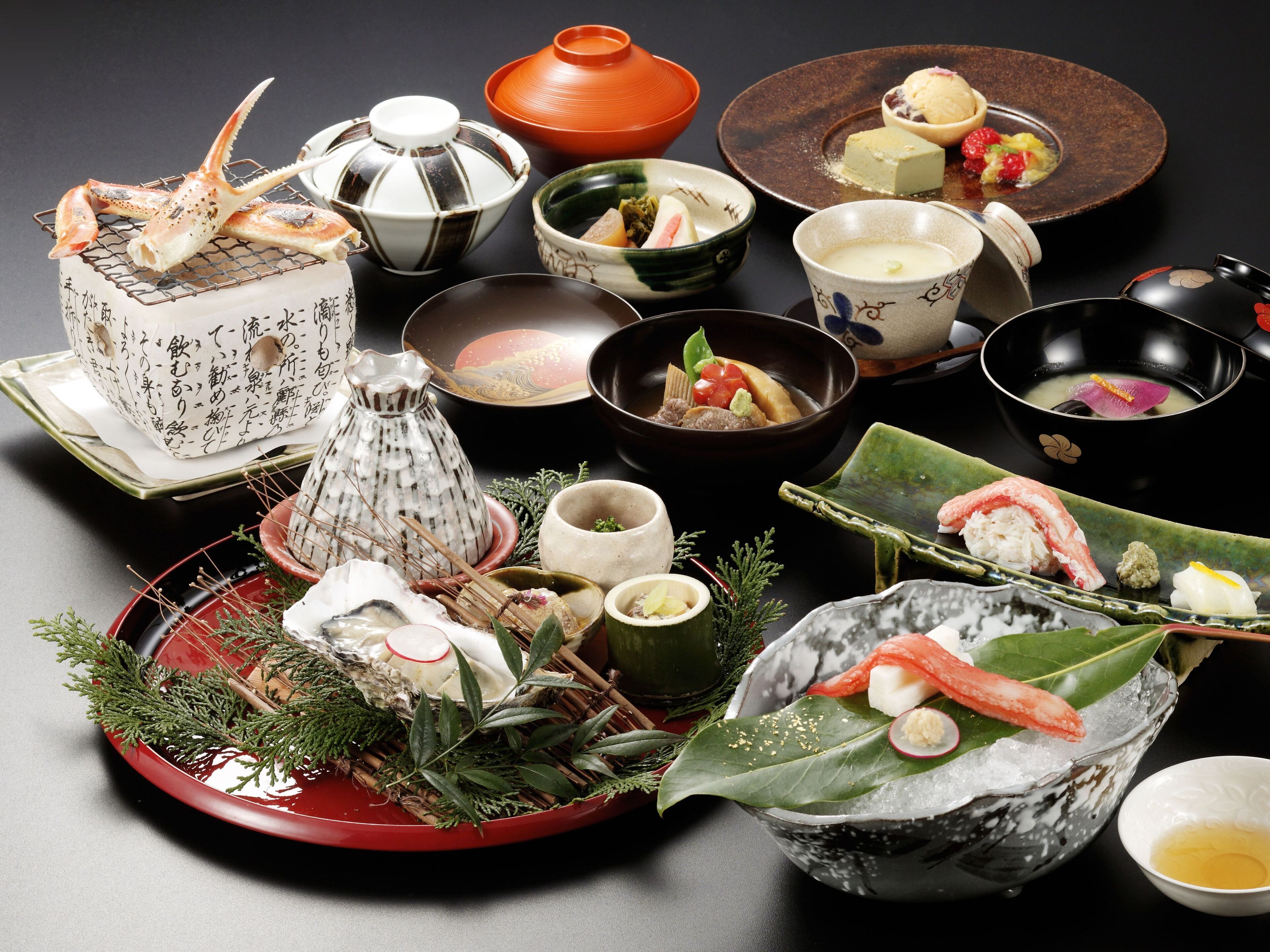 Variedad de platos y utensilios tradicionales japoneses, como sushi, sashimi y un juego de té, dispuestos sobre una mesa.