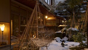 A traditional Japanese-style building with a wooden structure, a snow-covered garden, and a hanging bamboo decoration. - Kinjohro Kanazawa (Kanazawa)