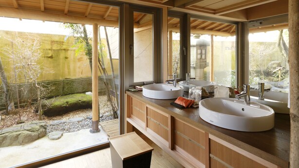 A modern bathroom with two large sinks, wooden cabinetry, and large windows offering a view of a garden. - Kinjohro Kanazawa (Kanazawa)
