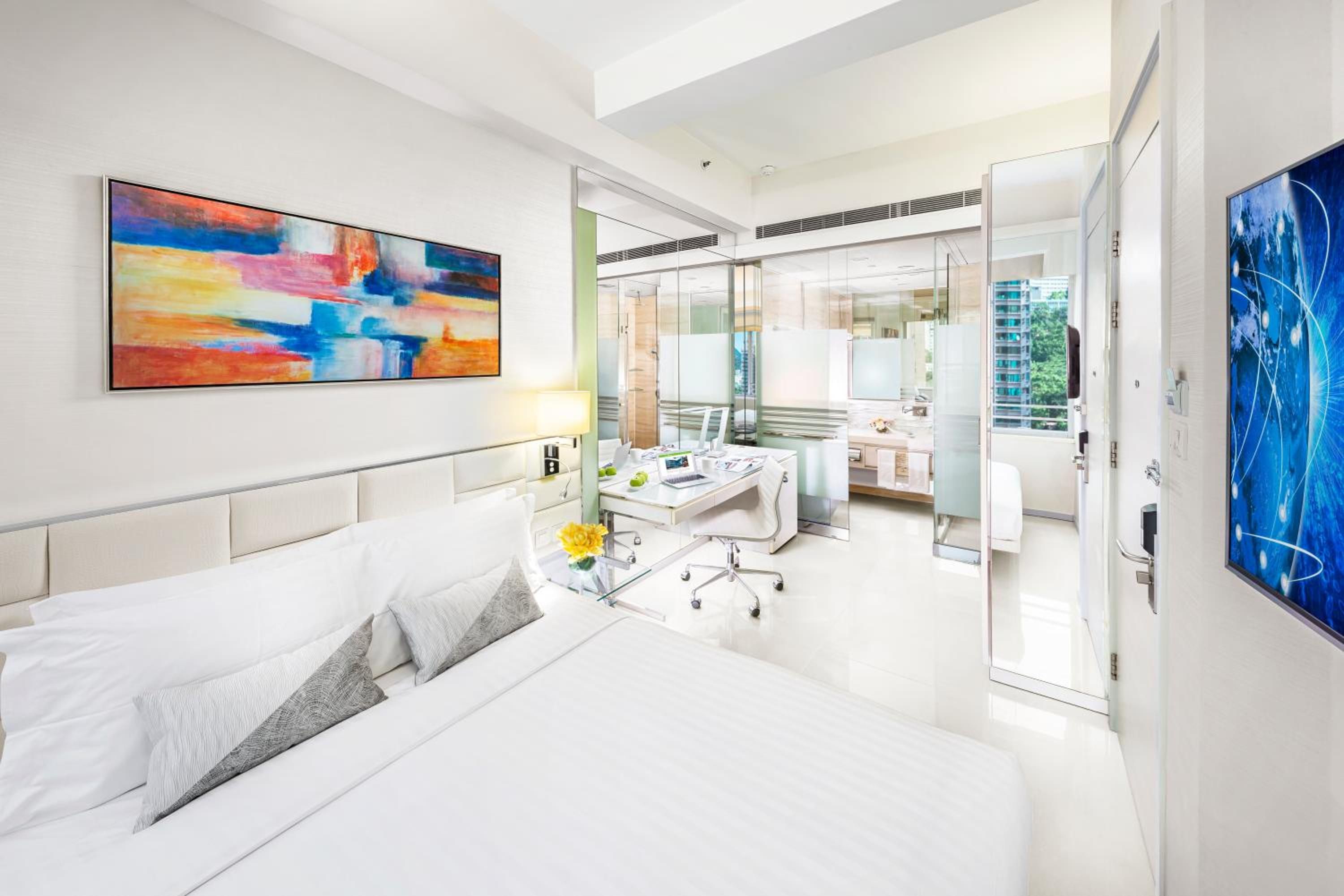 A hotel room with a bed, a desk, a chair, and a large window.