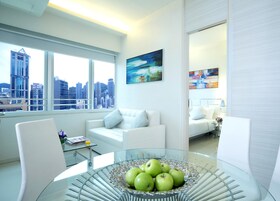 A modern living room with a glass coffee table, white sofas, and a city view through large windows.