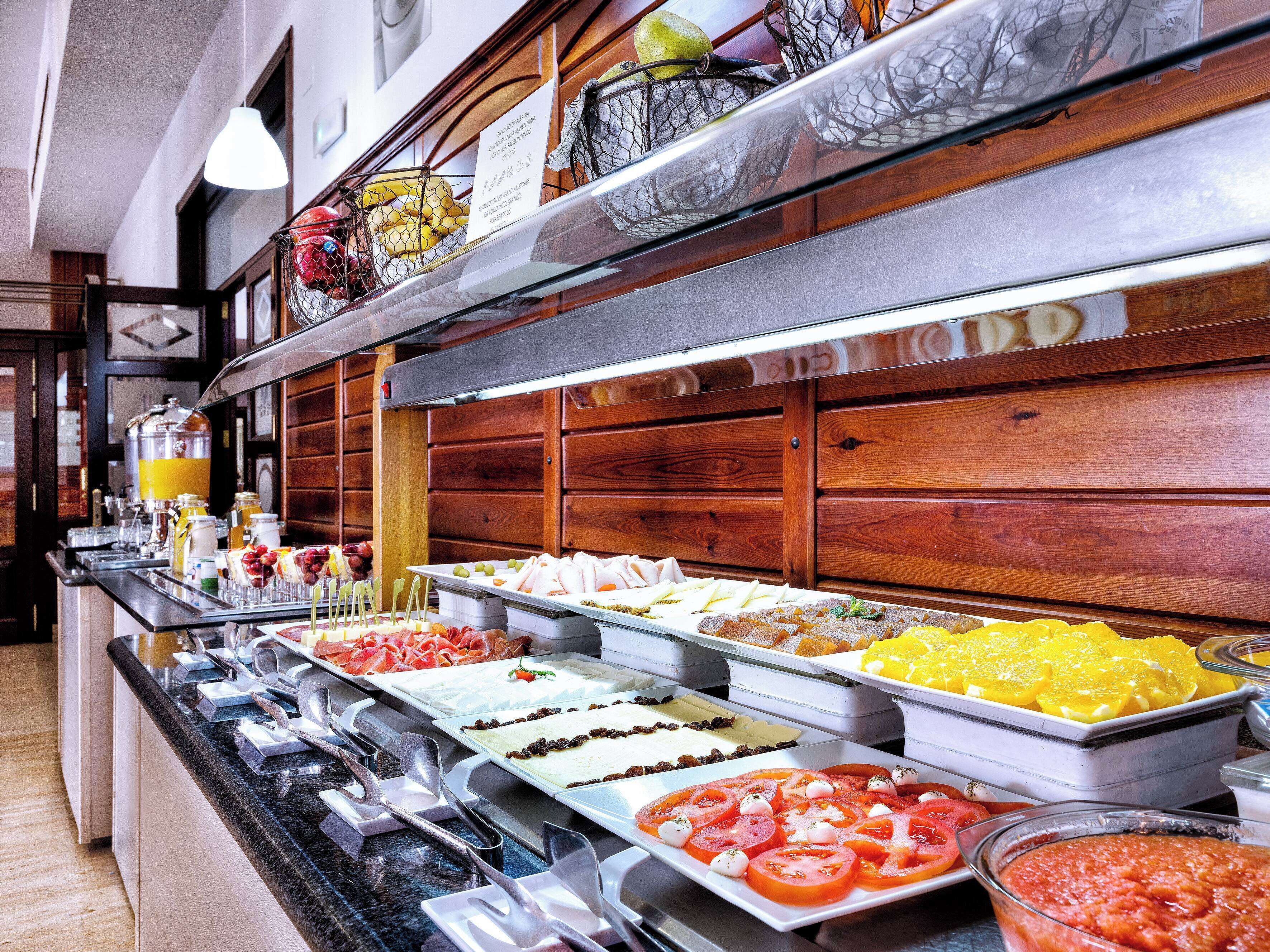A buffet with various food options including fruits, cheeses, and meats.