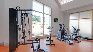 A gym with various exercise equipment, large windows, and a view of the outside.