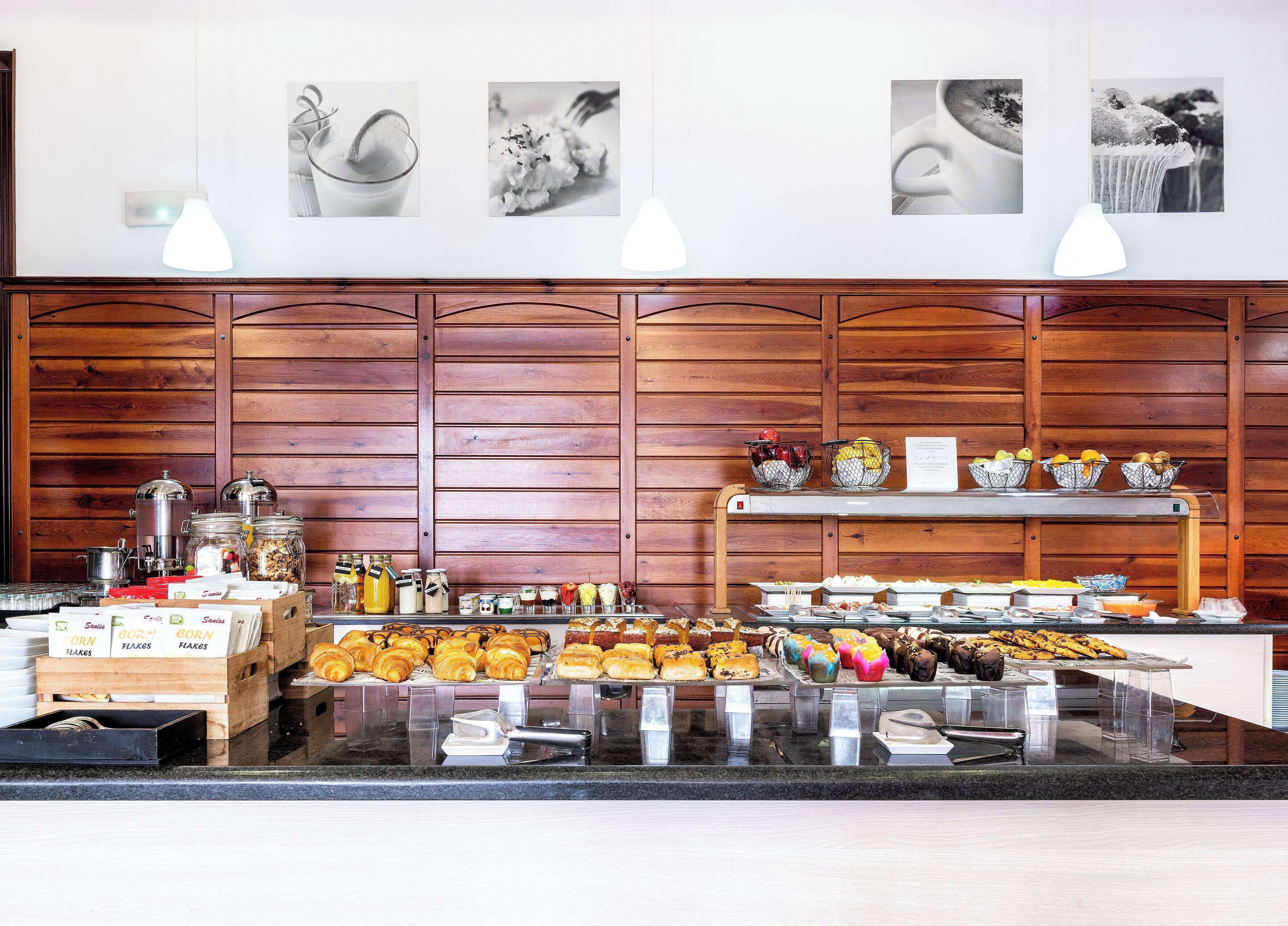 A buffet area with various food items, including pastries and fruits, and a coffee station.