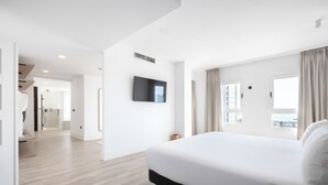 A modern hotel room with a large bed, a flat-screen TV mounted on the wall, and a view of the city through the window. - Hotel Melilla Puerto (Melilla)