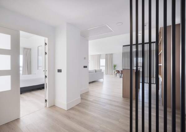 A spacious, modern hotel room with a large bed, a sitting area, and a dining space.