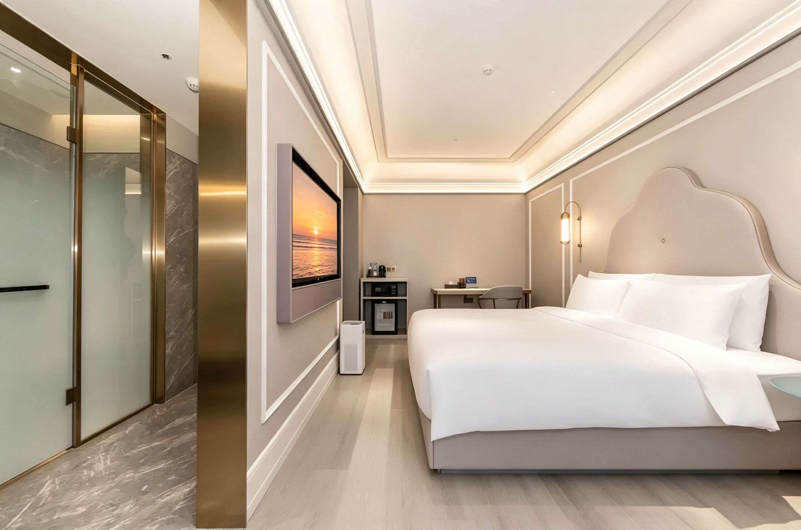A hotel room with a bed, a desk, a chair, a TV mounted on the wall, and a glass door closet.