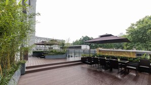 Um deck de madeira com mobiliário de exterior e um pérgula.