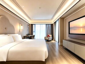 A modern hotel room with a large bed, a desk, a chair, and a television.
