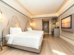 Ein Hotelzimmer mit einem großen Bett, Nachttischen, einem Fernseher und Blick auf den Sonnenuntergang.
