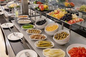 Ein reichhaltiges Buffet mit verschiedenen Speisen, darunter Obst, Gemüse und Soßen.