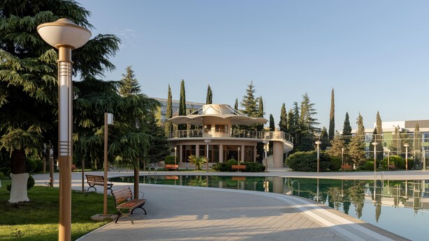 Un espace aménagé au bord de la piscine, comprenant un kiosque, des bancs et un lampadaire.