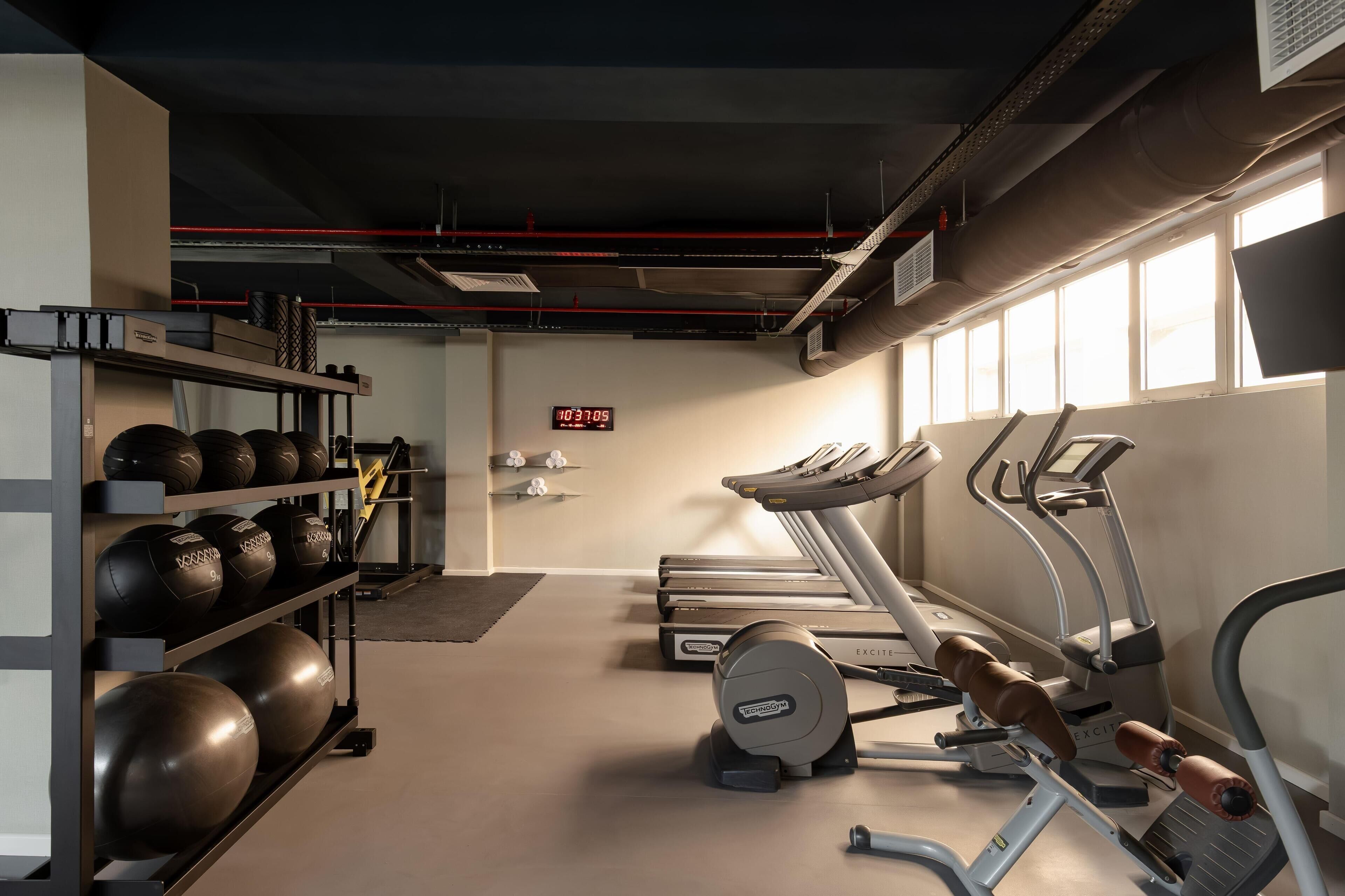 A gym with treadmills, elliptical machines, and a rack of medicine balls.