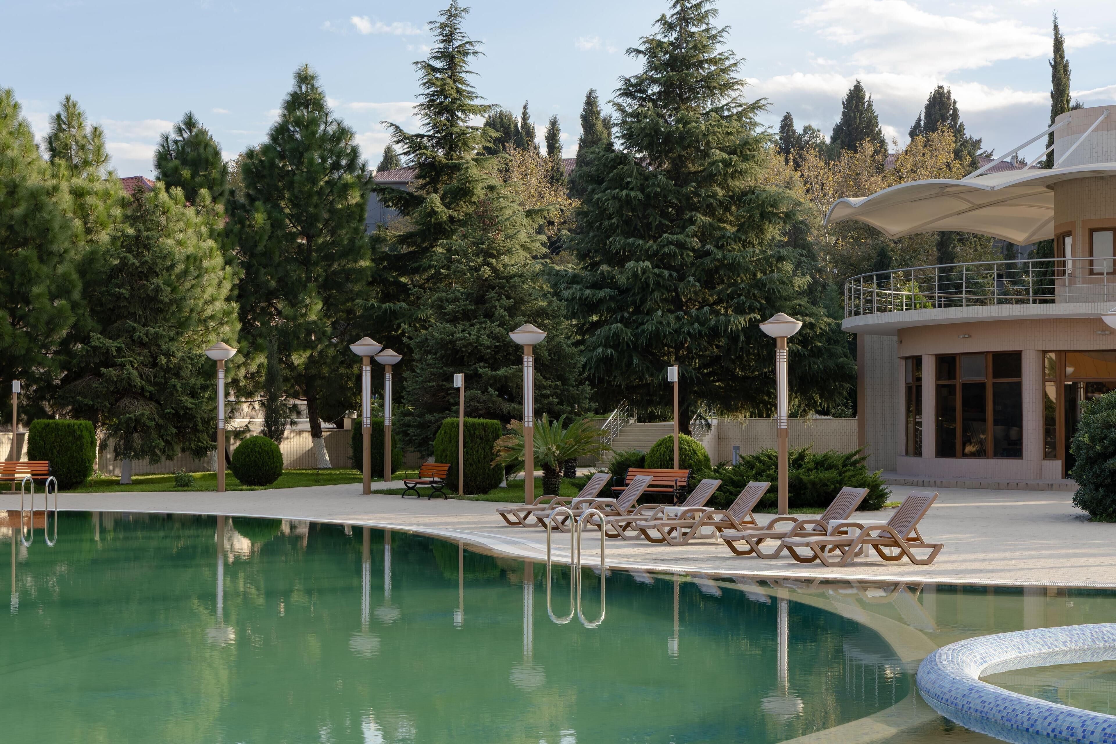 A swimming pool with lounge chairs and a building with a balcony.