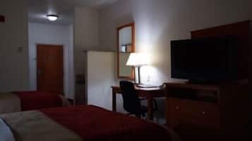 Une chambre d’hôtel avec deux lits, un bureau, une chaise, une télévision et une lampe.