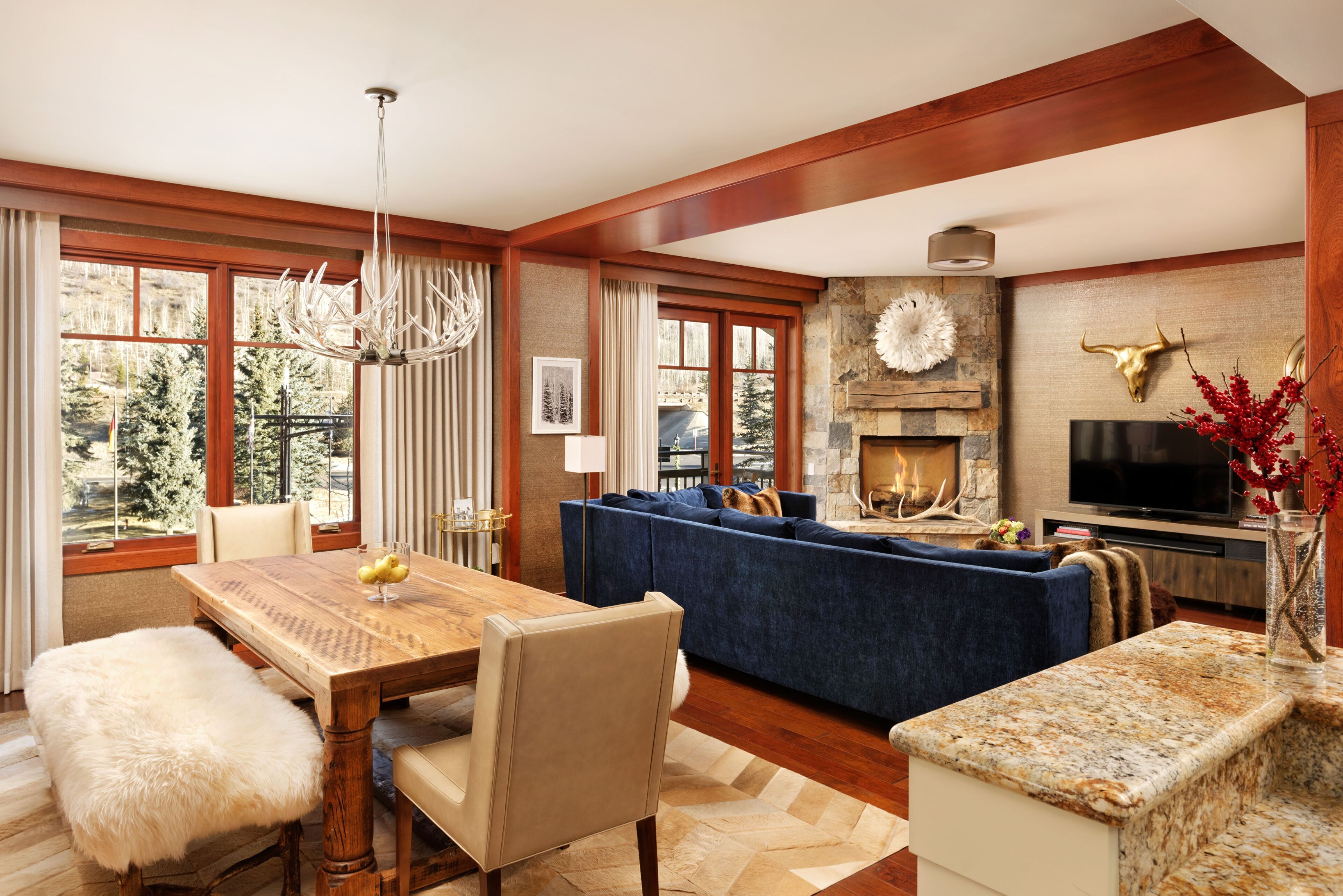 Amplia sala de estar con mesa de comedor de madera, sofá azul y chimenea de piedra.