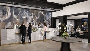 A reception area with a marble counter, a large abstract mural, and a round table with a floral centerpiece.