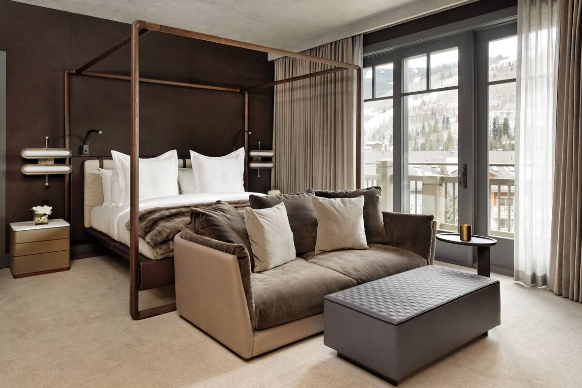 Ein modernes Schlafzimmer mit einem Himmelbett, einer Couch und einem kleinen Tisch.