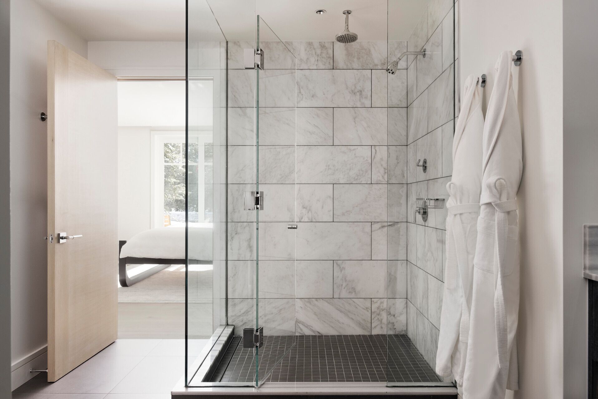 Un baño moderno con ducha de vidrio, azulejos de mármol y un toallero visible.