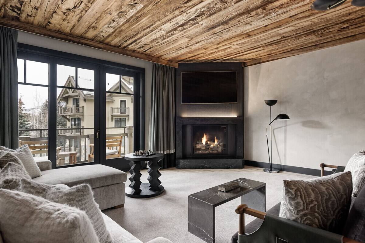 Ein modernes Wohnzimmer mit Kamin, großen Fenstern und Blick auf ein Gebäude.