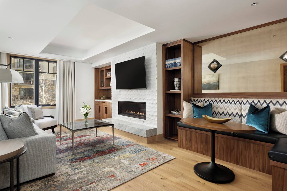 Ein modernes Wohnzimmer mit Kamin, einem flachbildfernseher an einer Steinwand und einer gemütlichen Sitzecke mit Sofa und Couchtisch.