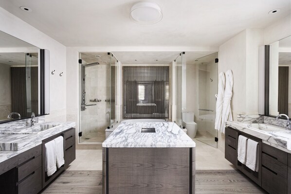 A modern bathroom with a large marble sink, dark wooden vanity, and a glass shower enclosure.
