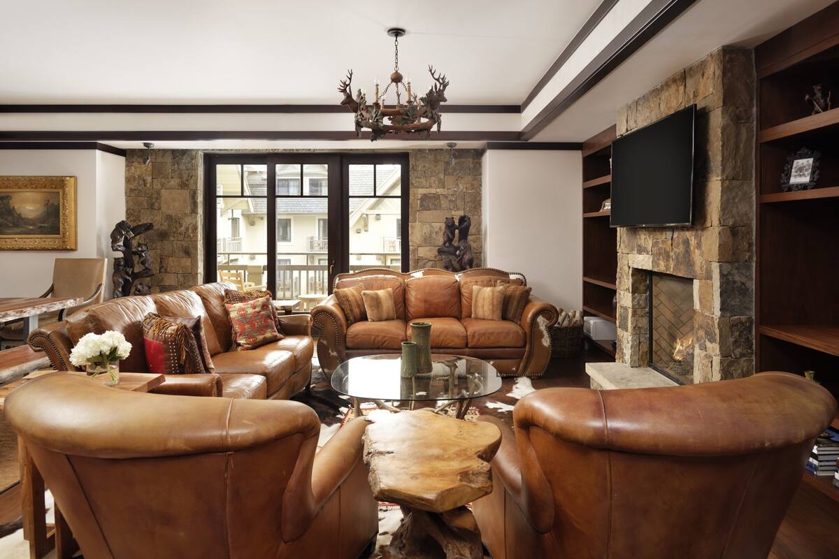 Ein Wohnzimmer mit Ledermöbeln, einem Steincheminée und einem Wand-Fernseher.