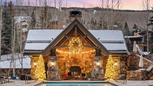 A cozy lodge with a stone fireplace, a pool, and Christmas decorations. - Four Seasons Resort and Residences Vail (Vail)