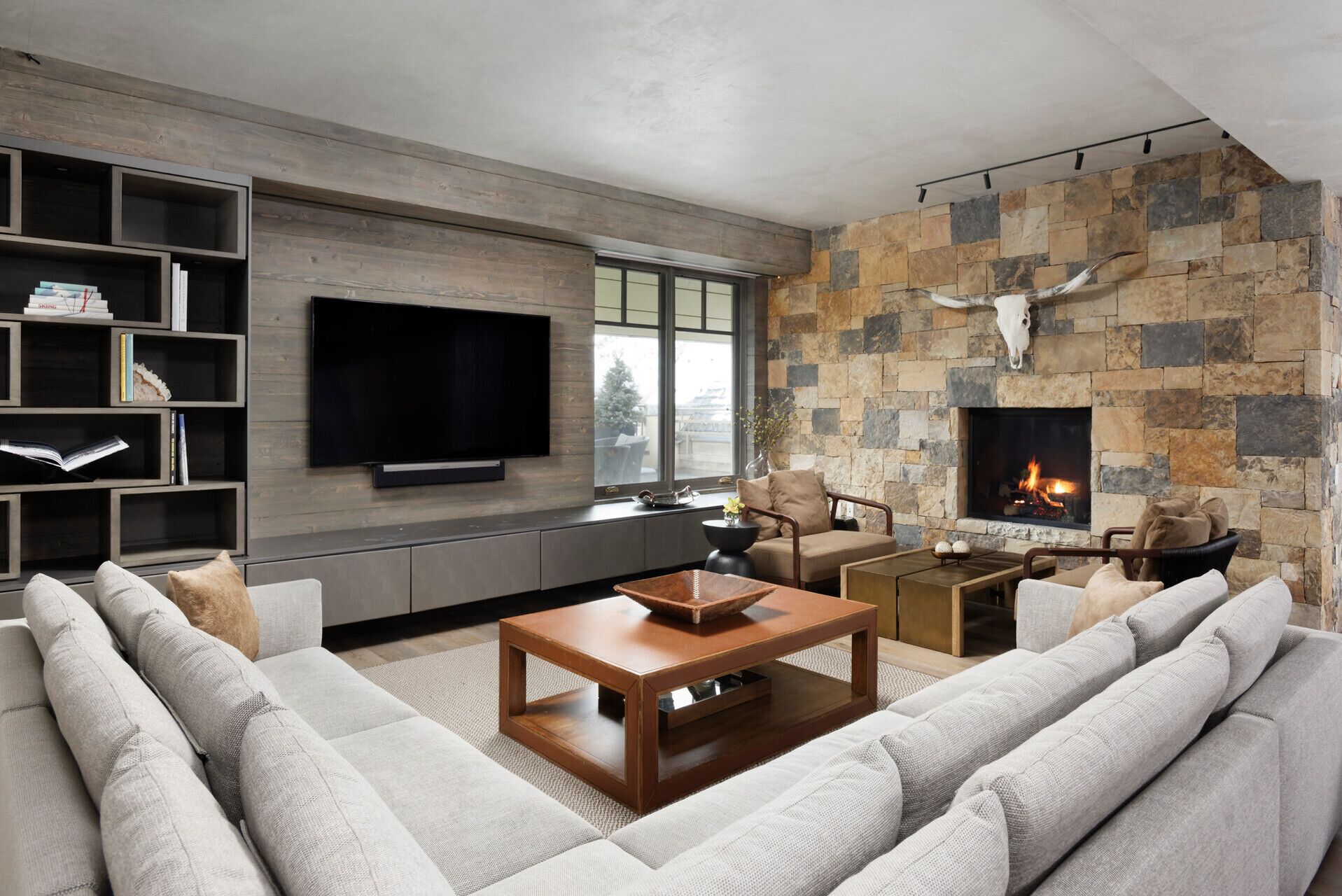 A modern living room with a stone fireplace, a flat-screen TV, and a cozy seating area.