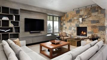 A modern living room with a stone fireplace, a flat-screen TV, and a cozy seating area.