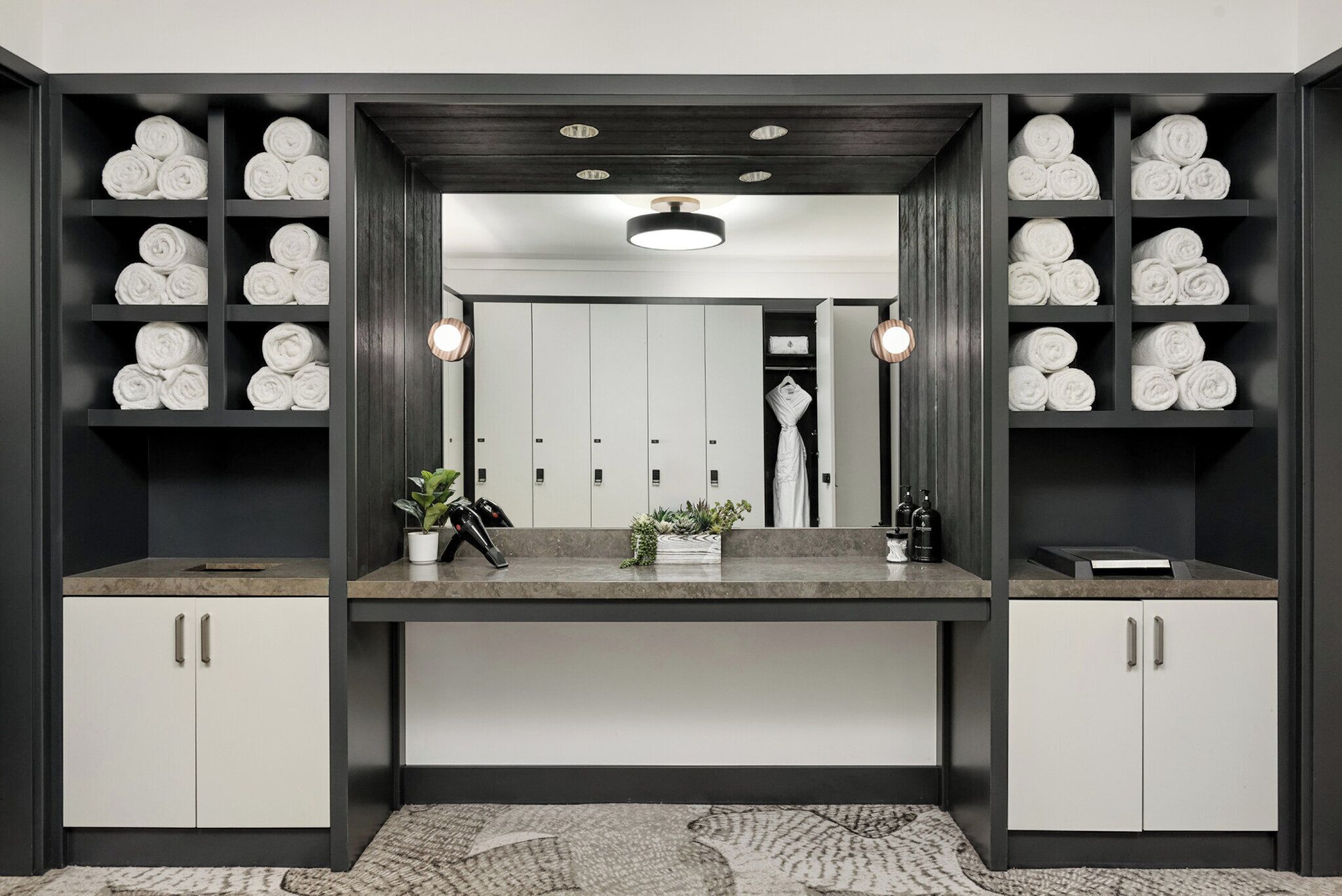 A modern bathroom with a central vanity, towel racks on either side, and a mirror above the vanity.