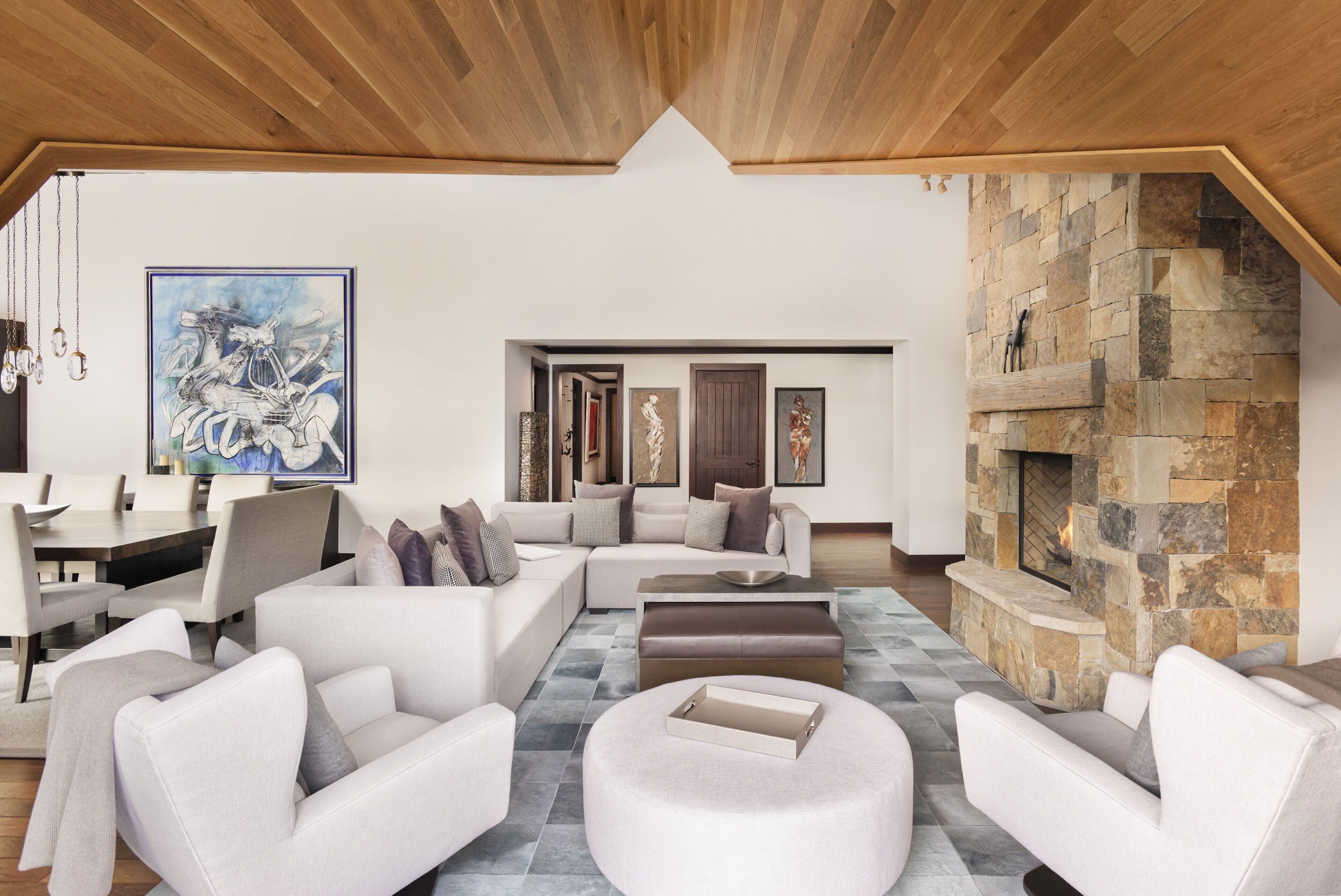 A spacious living area with a stone fireplace, a dining area with a large table, and a modern ceiling design.