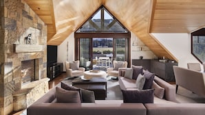 A spacious living room with a stone fireplace, modern furniture, and a large skylight. - Four Seasons Resort and Residences Vail (Vail)