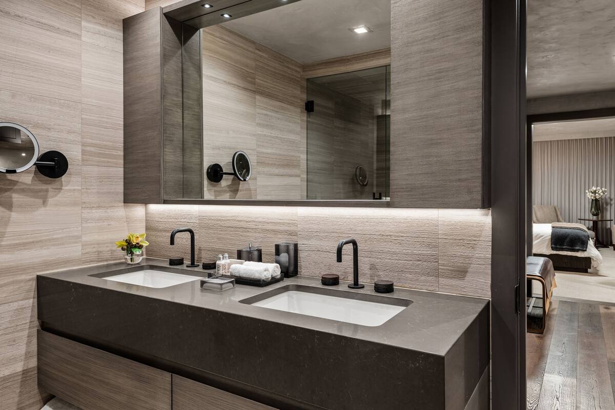 Ein modernes Badezimmer mit zwei Waschbecken, einem großen Spiegel und einem kleinen, runden Spiegel.