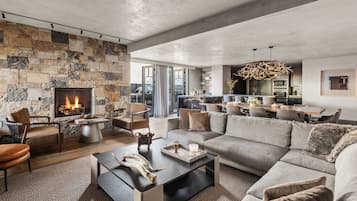 A modern living room with a stone fireplace, a dining area, and a kitchen.