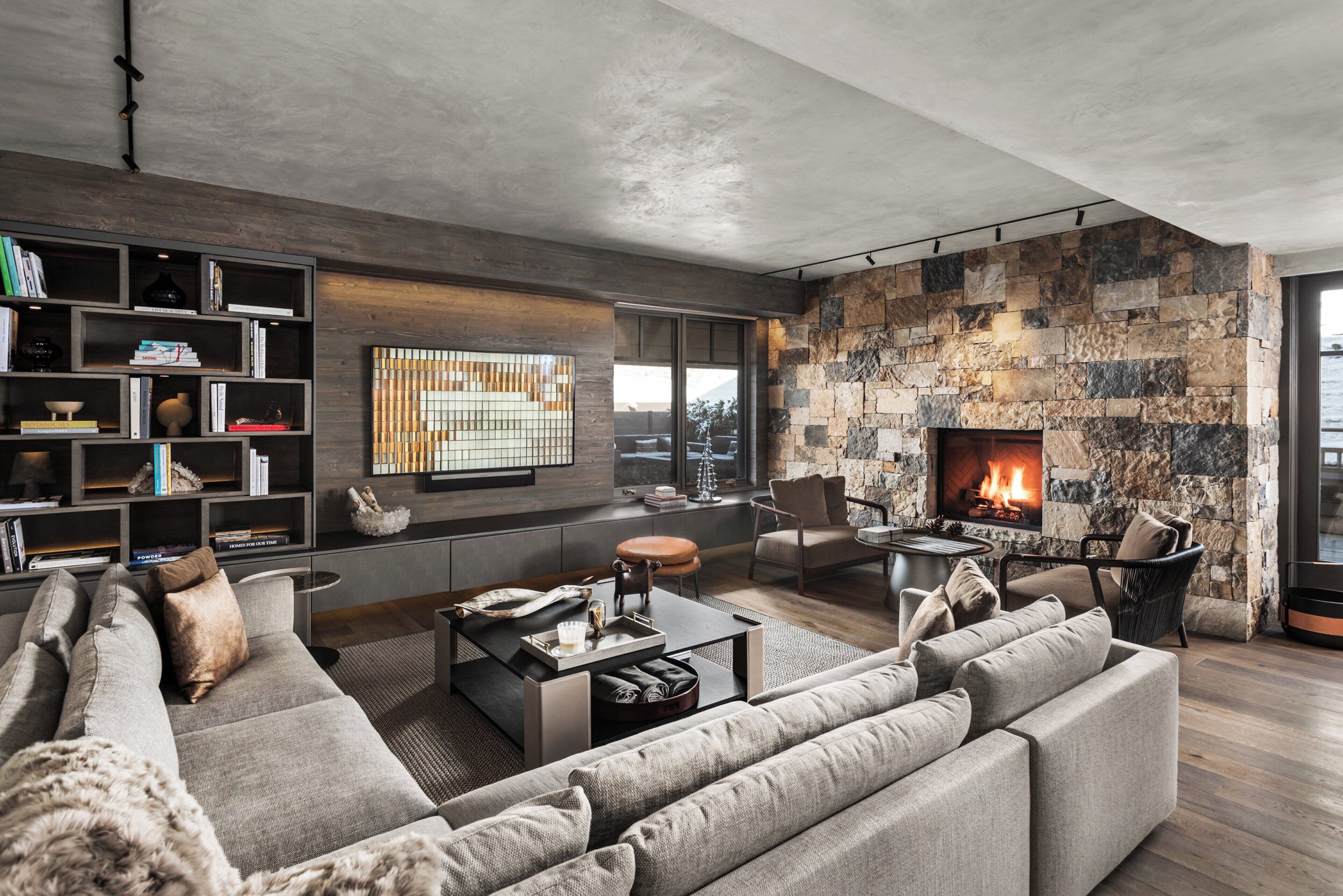 Una sala de estar moderna con chimenea de piedra, una amplia estantería y un espacio de descanso acogedor.