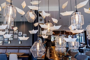 Interior de restaurante com lanternas de papel penduradas, luminárias pendentes e um espaço de bar.