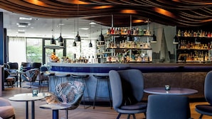 A modern bar area with round tables, bar stools, and a variety of bottles on shelves. - Motel One Hamburg-Alster (Hamburg)