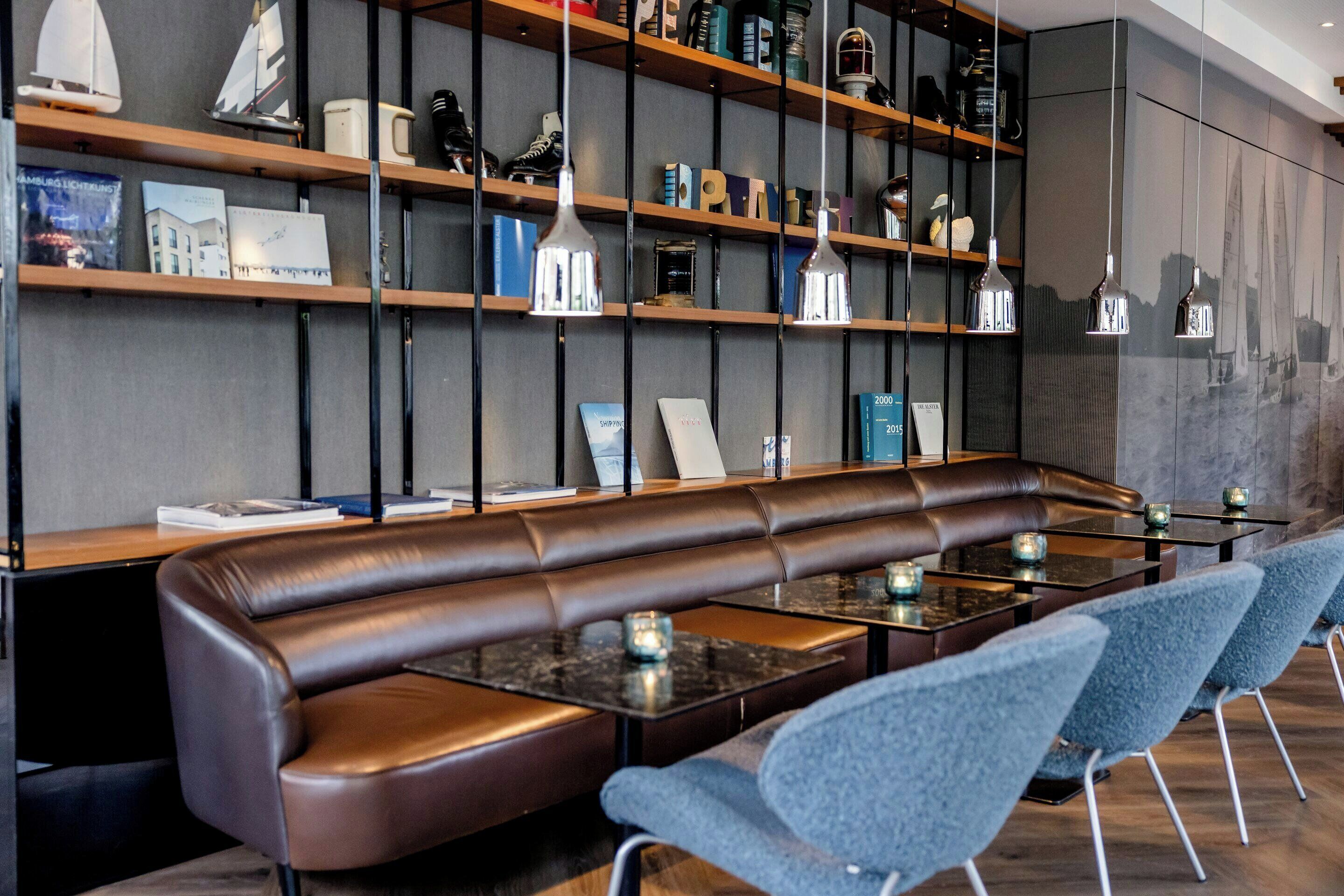 A modern interior with a leather booth seating area, bookshelves, and pendant lighting.