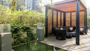 A covered outdoor seating area with a pool, surrounded by greenery and a cityscape. - Motel One Hamburg-Alster (Hamburg)