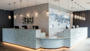 A reception area with a speckled granite counter, pendant lighting, and a large wall mural. - Motel One Hamburg-Alster (Hamburg)